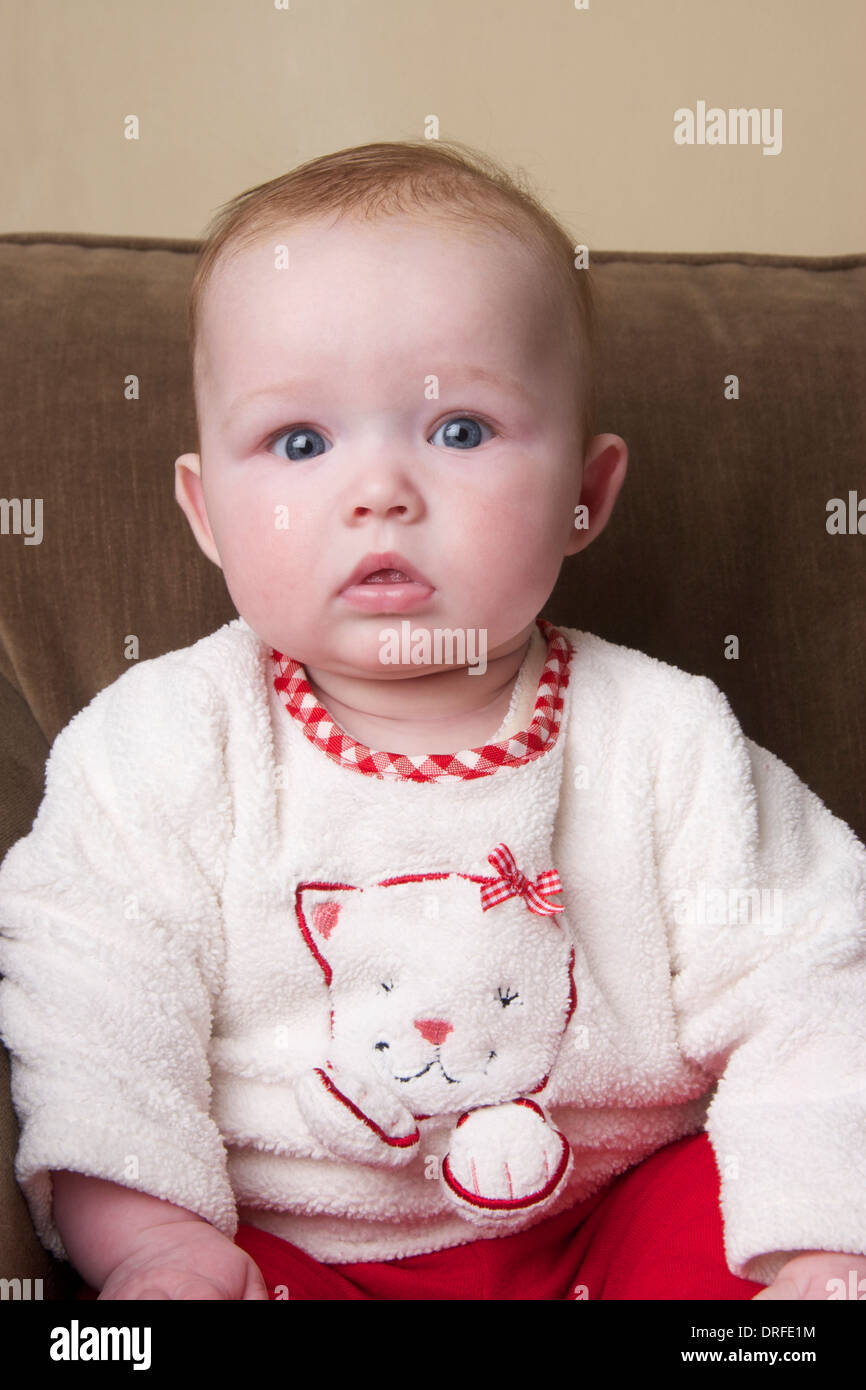 Portrait de 5 mois baby girl sitting on sofa Banque D'Images