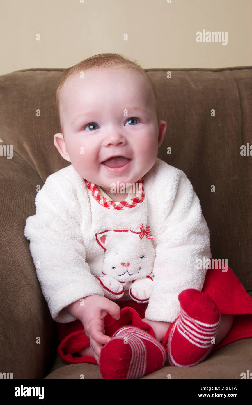 Portrait de 5 mois baby girl sitting on sofa Banque D'Images