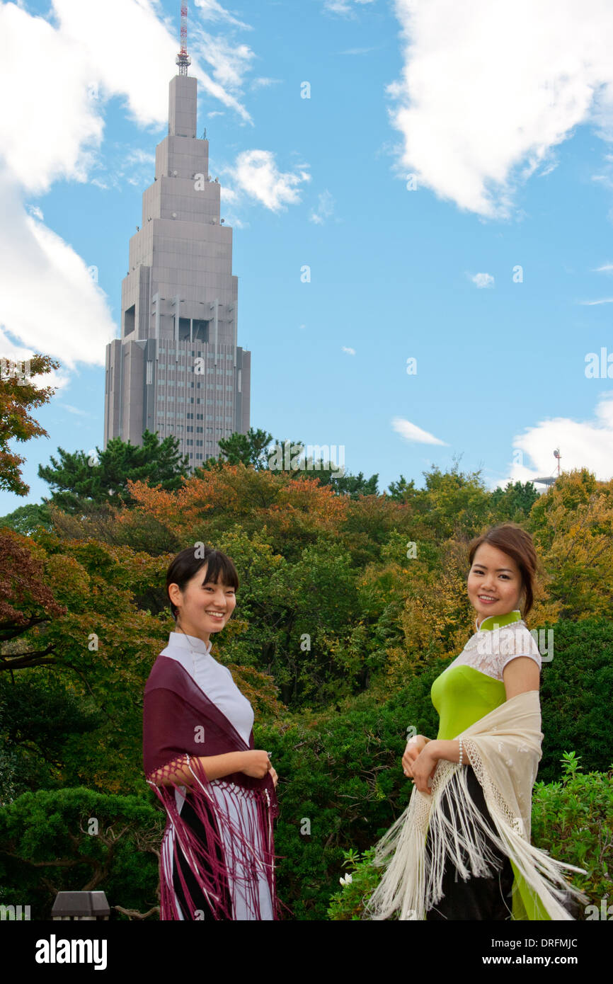 Deux jeunes femmes dans un Ao Dai à Shinjuku Park en face de NTT Docomo Yoyogi Building Banque D'Images