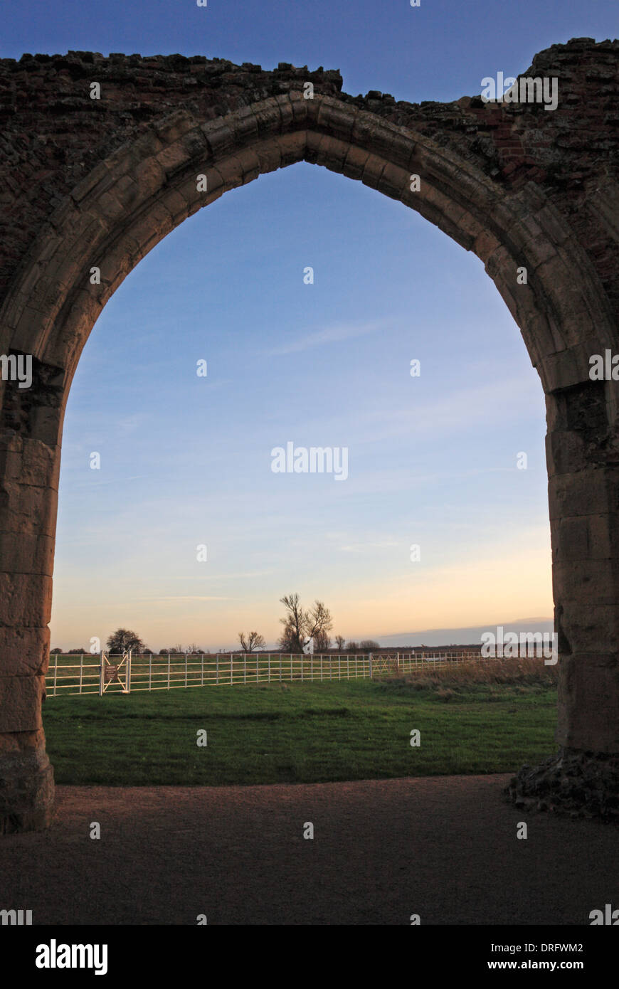 Une vue sur le coucher du soleil à travers les ruines de west gatehouse arch at St Benet's Abbey, près de Horning, Norfolk, Angleterre, Royaume-Uni. Banque D'Images