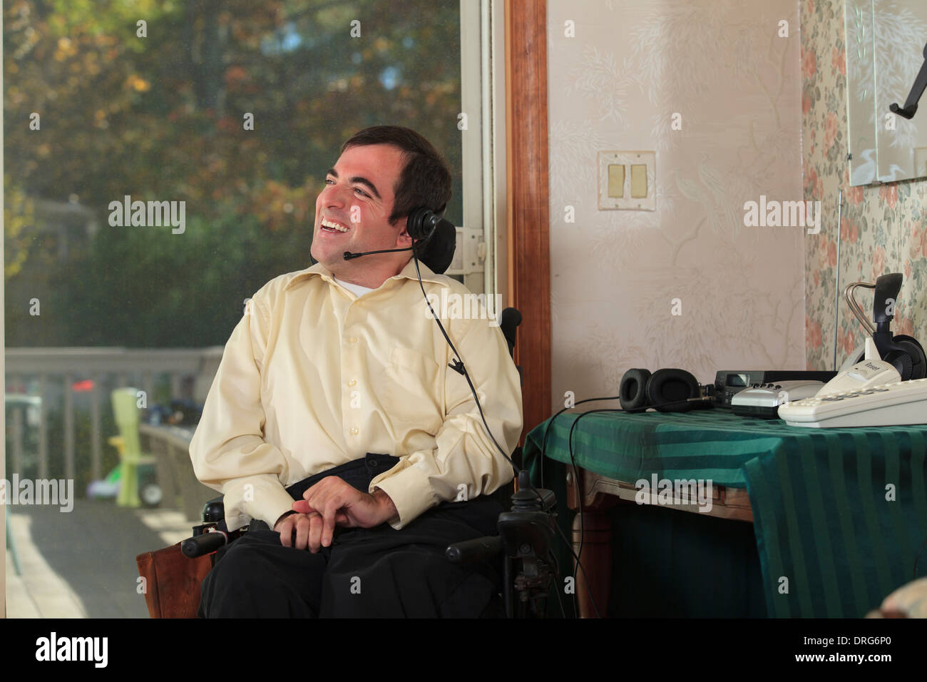 L'homme souffrant de paralysie cérébrale en fauteuil roulant motorisé à l'aide de ses écouteurs Banque D'Images