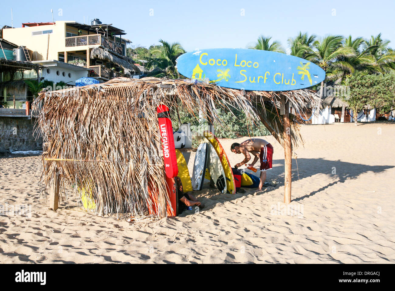 Surf Club beach abri avec toit palapa où les membres peuvent stocker pour pignons et des planches durant la journée quand ils viennent dans le surf Banque D'Images