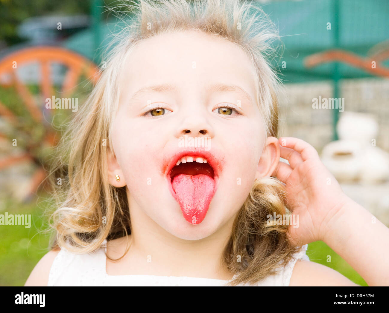 Petite fille avec sa langue. La fille est à la caméra et à son expression est drôle. Banque D'Images