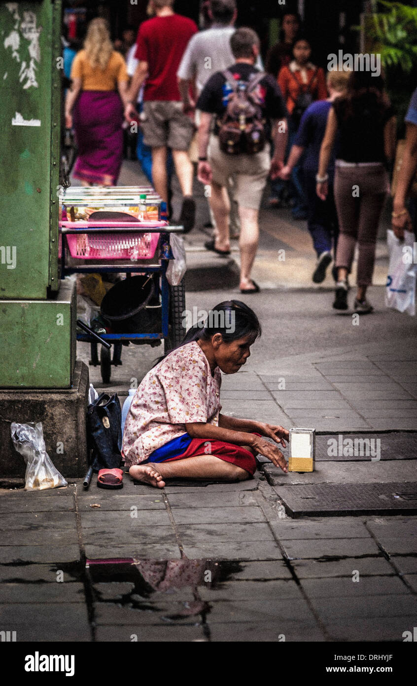 Femme sans-abri mendiant sur l'asphalte, Bangkok. Banque D'Images