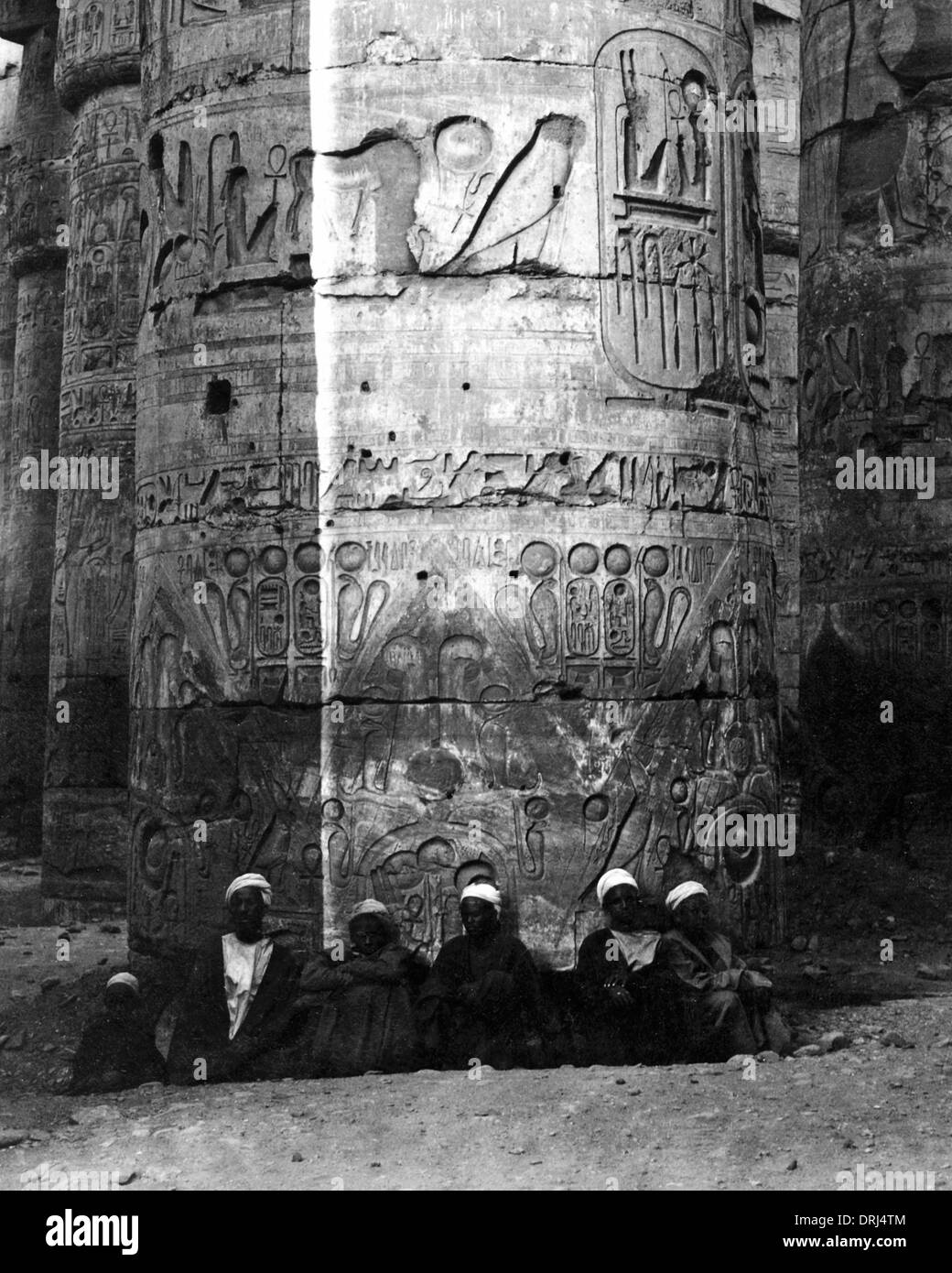 Les hommes assis à la base de la colonne, Karnak, Egypte Banque D'Images