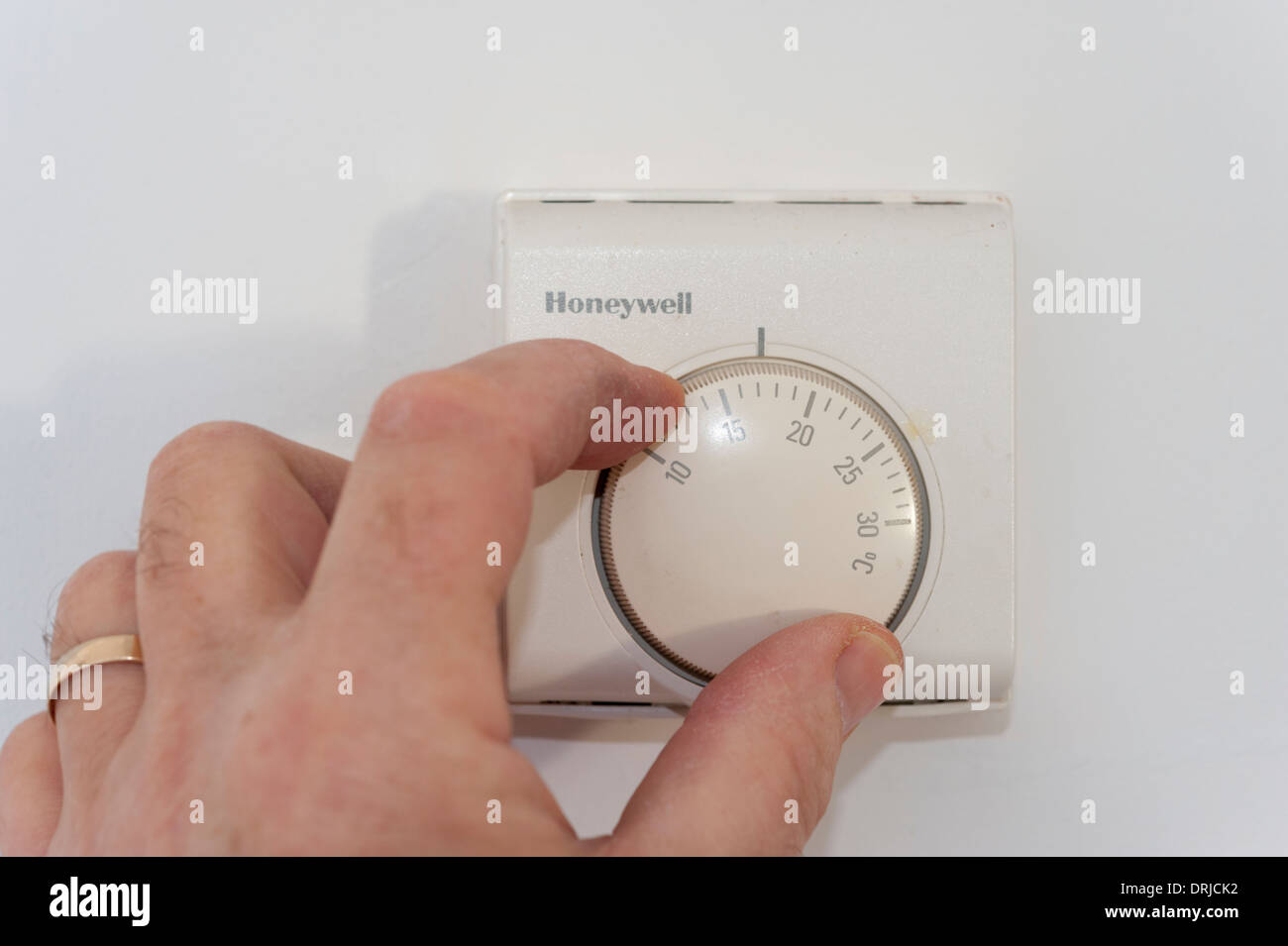 Gros plan d'une part le fait de baisser ou de régler la température sur un thermostat de chauffage domestique Banque D'Images