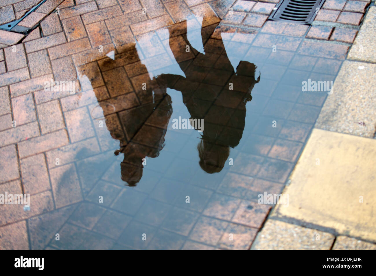 Reflets de personnes marchant dans une flaque d