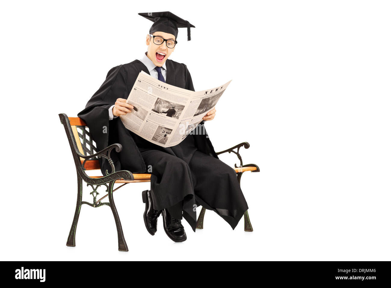 Guy excité in graduation gown lire un journal assis sur un banc Banque D'Images