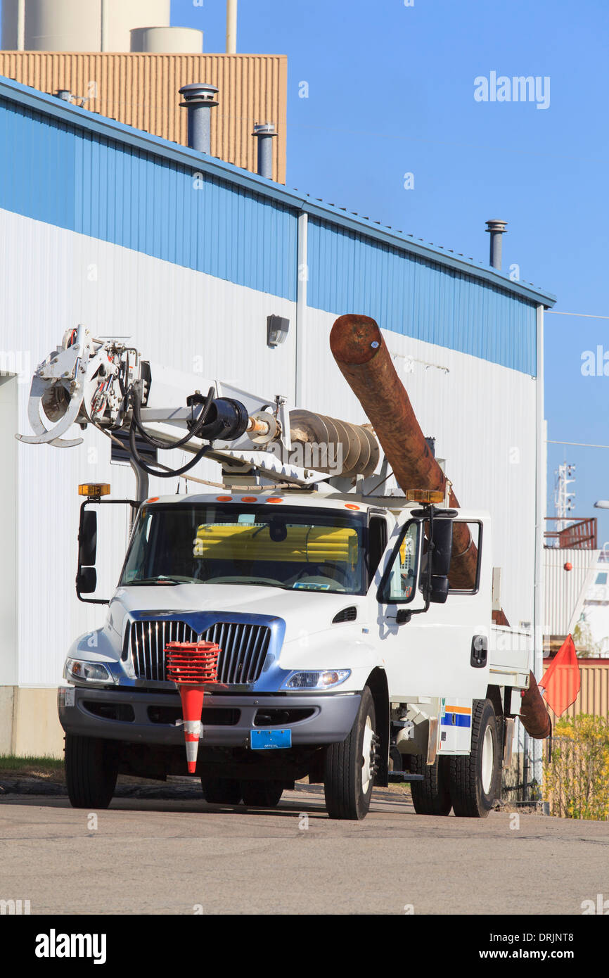 Camion utilitaire avec perceuse hydraulique pour l'installation d'un nouveau pôle de puissance à côté de centrales électriques Banque D'Images