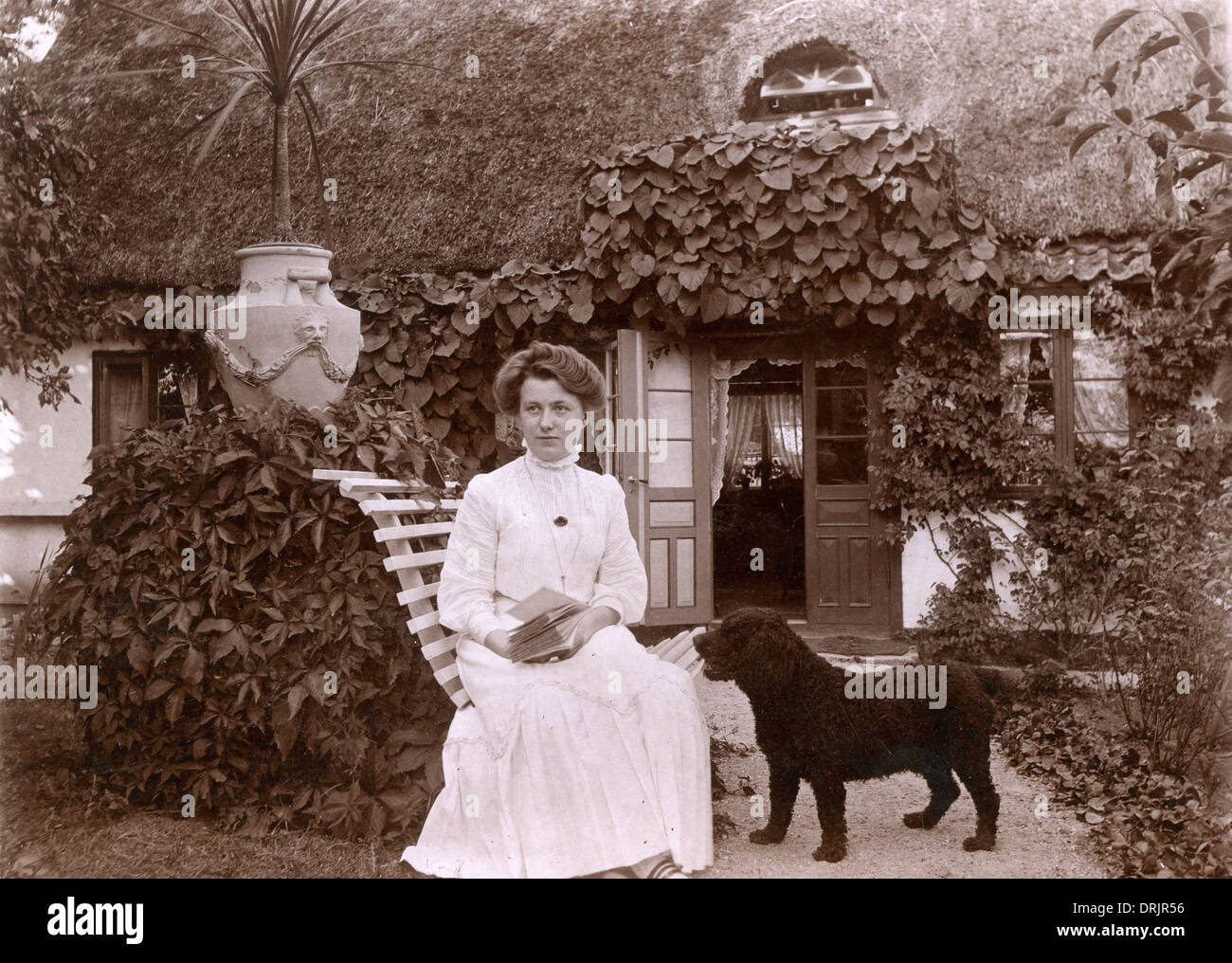 Une femme vêtue de blanc avec un petit chien aux cheveux noirs frisés Banque D'Images