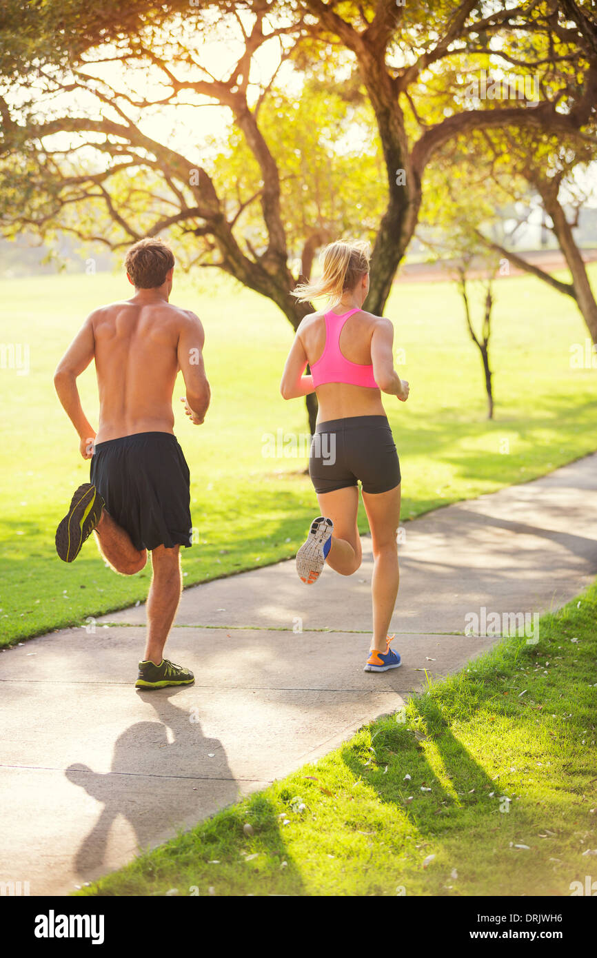 Couple jogging courir à l'extérieur dans le parc, au lever du soleil sur le magnifique sentier. De vie sain concept de remise en forme. Banque D'Images