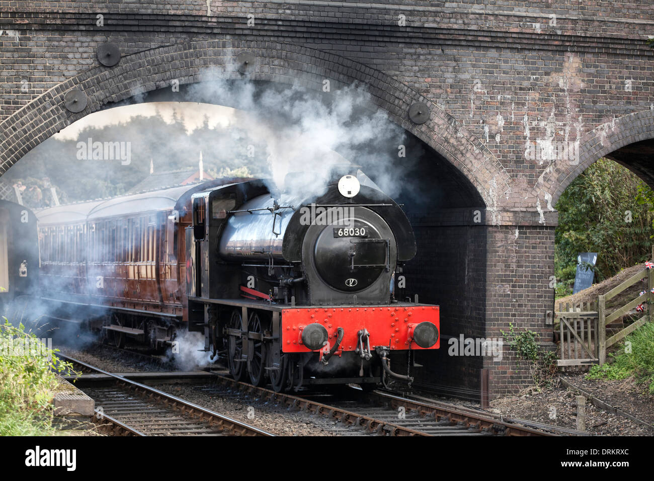 Train à vapeur passant sous pont de briques Banque D'Images