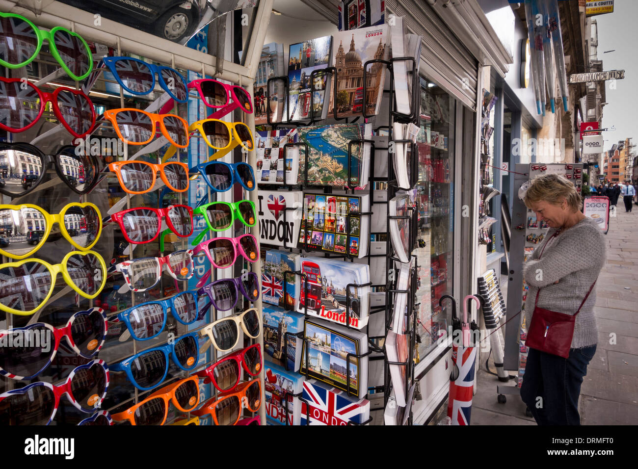 Un touriste à la recherche de divers souvenirs affichés à l'extérieur d'une boutique à Londres, Royaume-Uni Banque D'Images