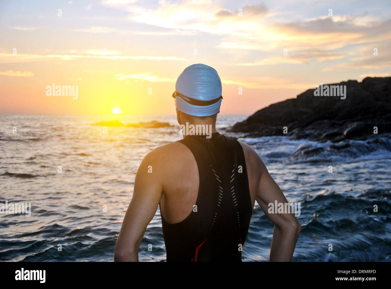 Jeune athlète de triathlon de/d'un lever de soleil sur la mer Banque D'Images
