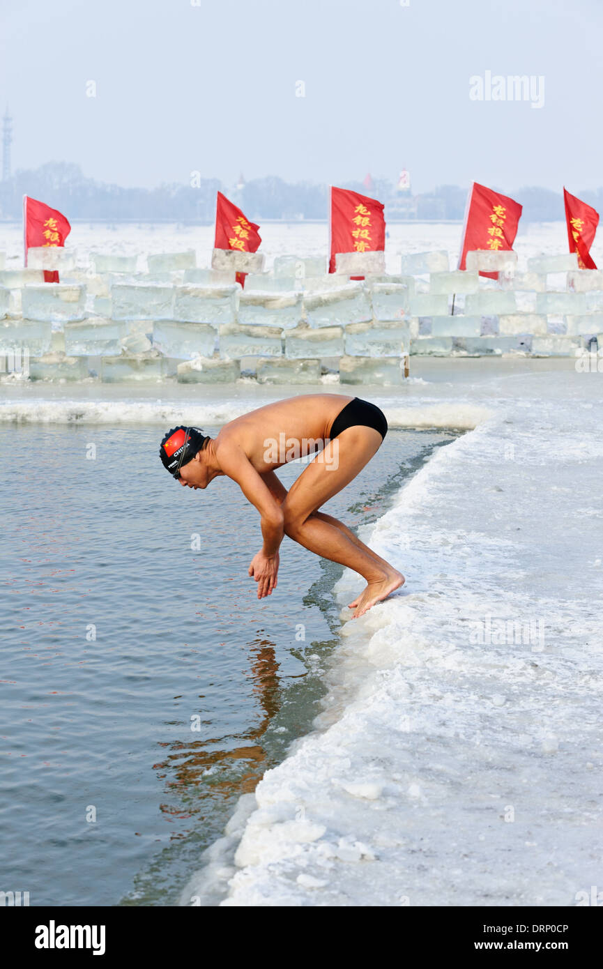 La nageuse de glace plonge dans l'eau froide de la rivière Songhua, Harbin, Chine. Un trou dans la glace est maintenu ouvert pour les nageurs. Banque D'Images