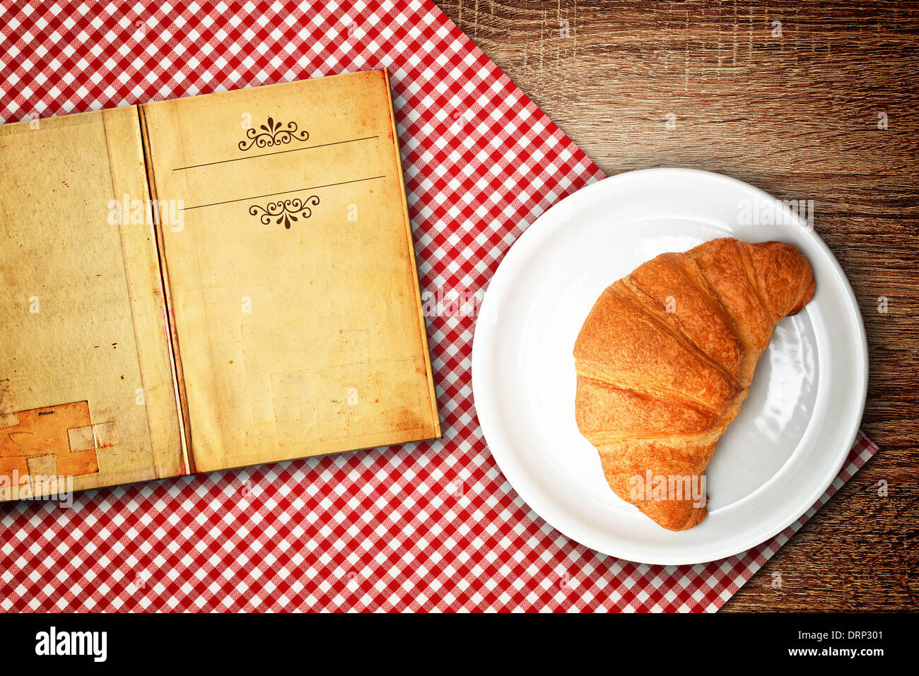 Recette de croissant. Croissant sur une plaque et un vieux livre avec l'exemplaire de l'espace pour votre texte. Banque D'Images