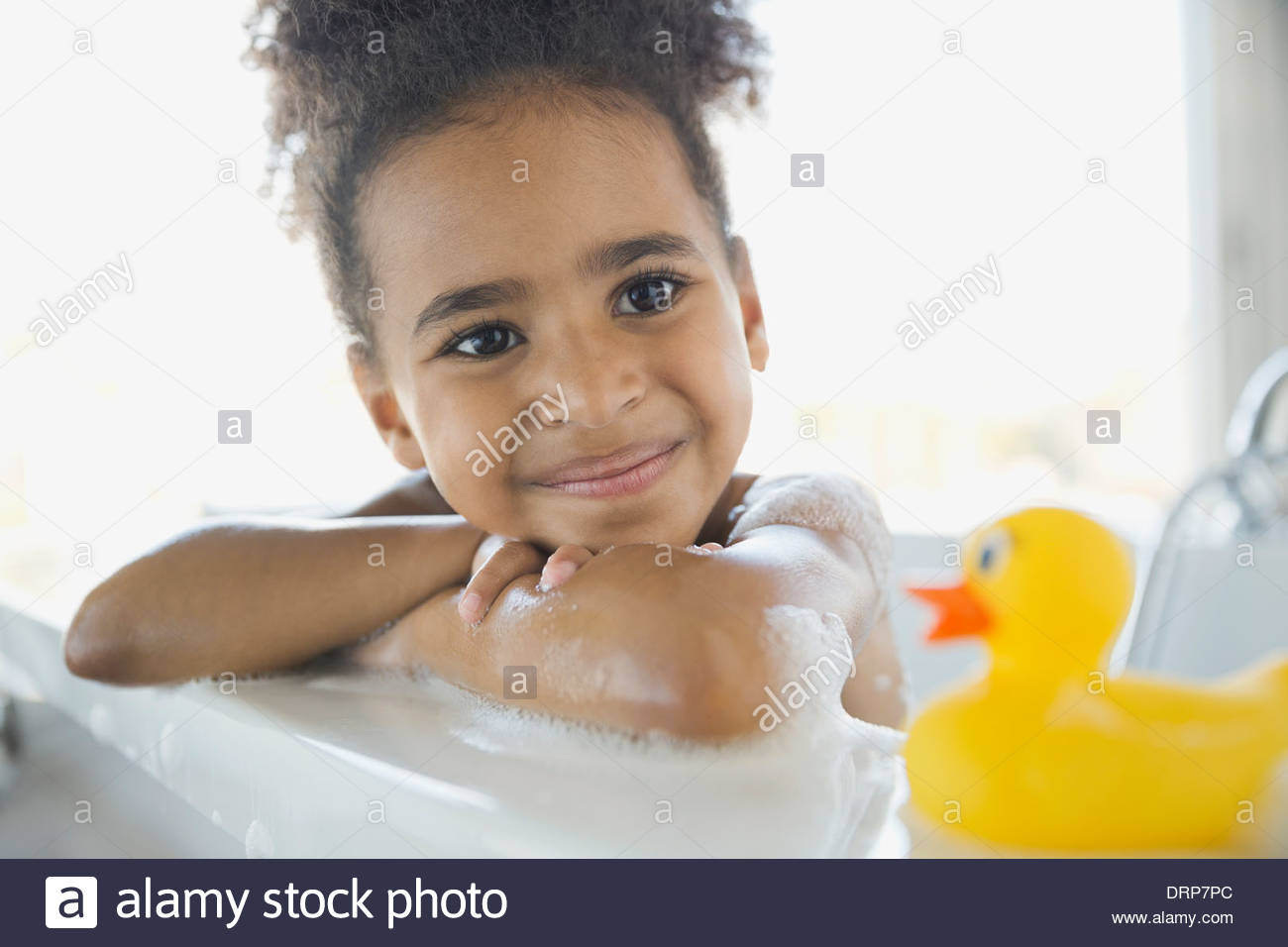 Fille dans un bain de mousse avec rubber duck Banque D'Images