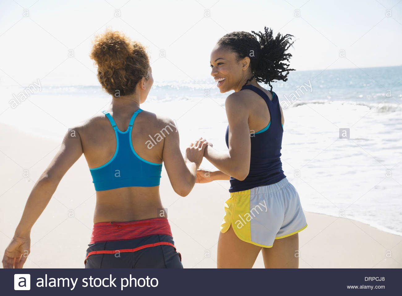 Female friends jogging on beach Banque D'Images
