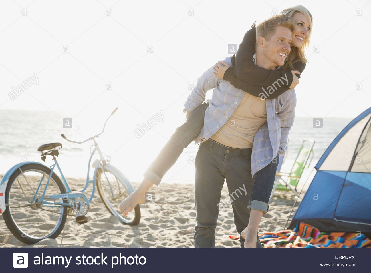 Man piggybacking woman on beach Banque D'Images