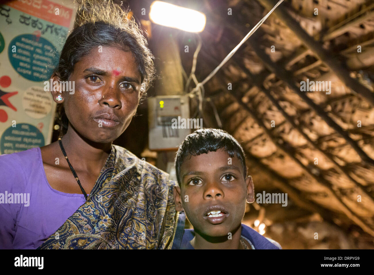 Un intouchable femme dans sa hutte, éclairé par une lumière électrique, alimenté par un panneau solaire de format A4, Banque D'Images