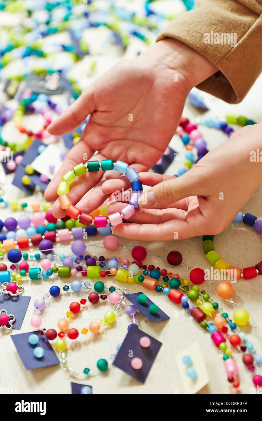 Les mains tenant bracelet bijoux colorés dans un magasin Banque D'Images