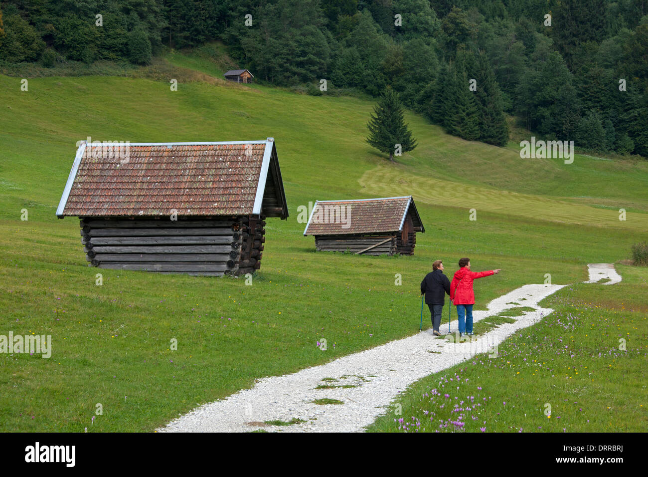 Les touristes passant par cabanes de bois / greniers le long du lac Gerold / Geroldsee près de Mittenwald, Haute-Bavière, Allemagne Banque D'Images