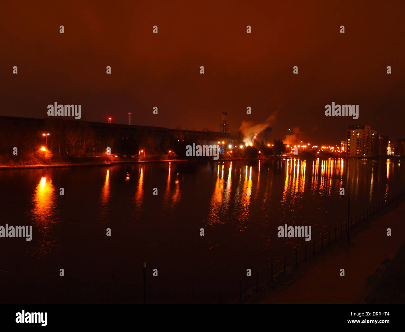 Dock à Cardiff Bay dans la nuit avec des lumières se reflétant dans l'eau et de vapeur à partir d'un site industriel à l'arrière-plan Banque D'Images