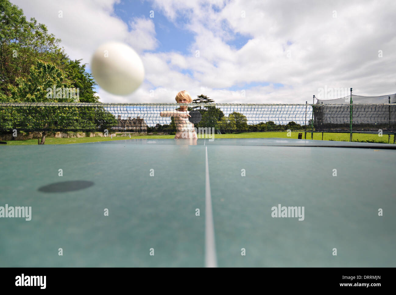 Un garçon renvoie une balle de tennis de table sur le net Banque D'Images