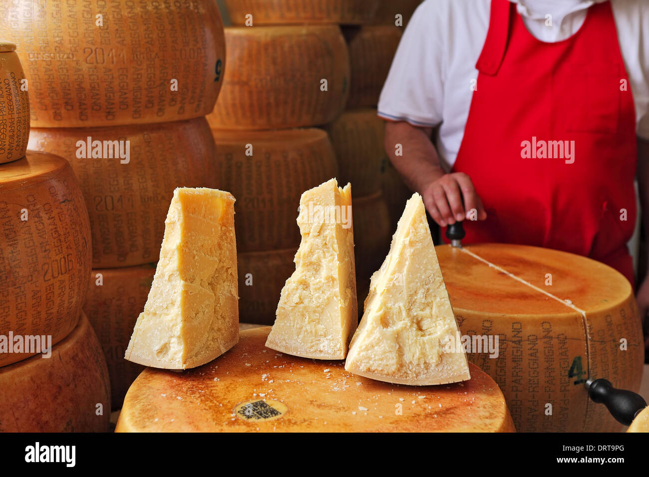Couper des morceaux et les roues de Parmesan - fromage italien fabriqué à partir de lait cru de vache. Banque D'Images