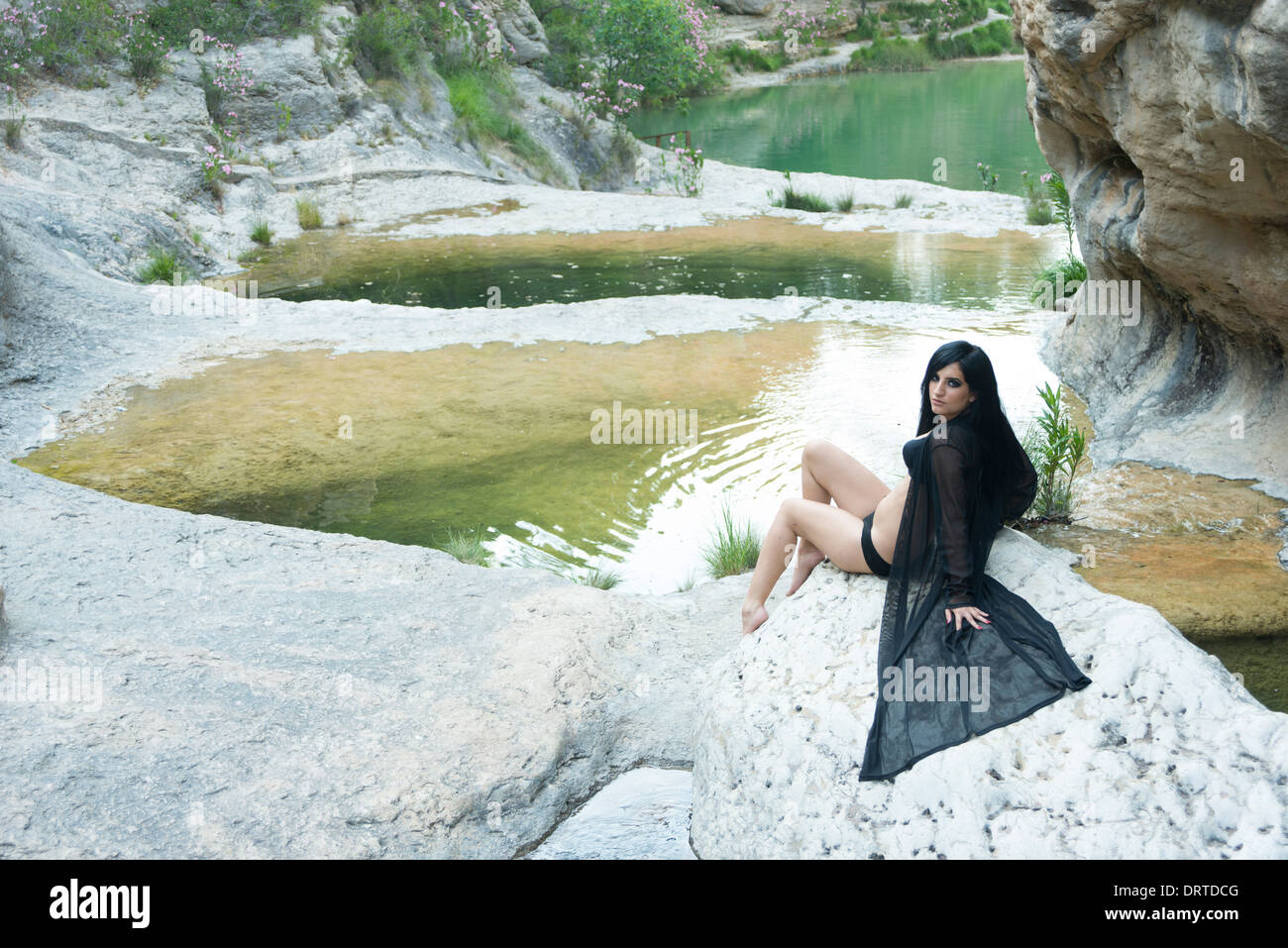 Modèle féminin posant allongé sur le rocher à côté de la rivière Banque D'Images