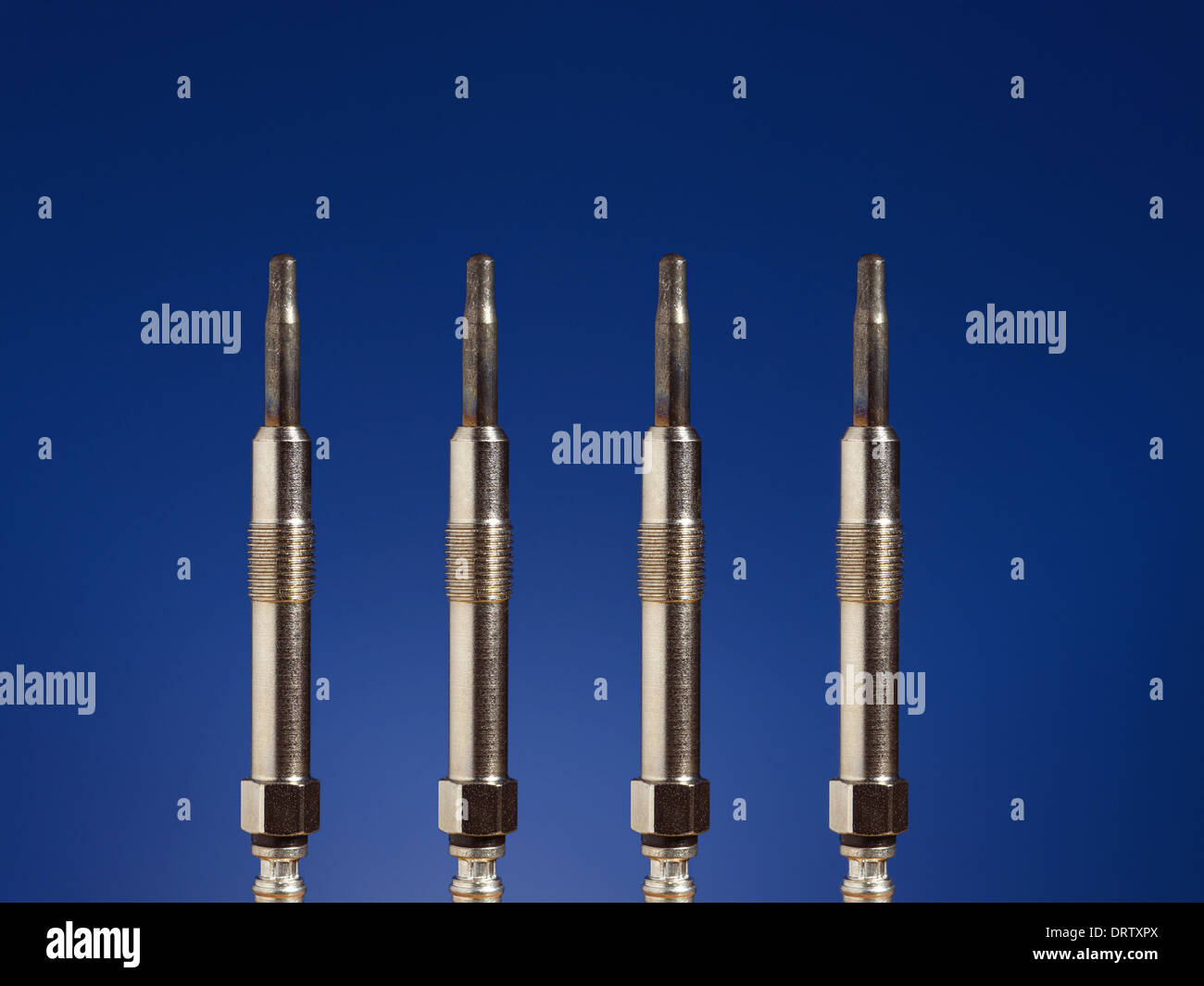 Quatre bougies de préchauffage du moteur diesel tourné sur fond bleu foncé Banque D'Images