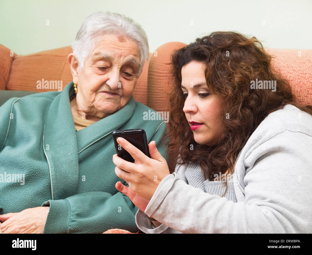 Petite-fille et grand-mère à l'aide d'un smartphone à l'intérieur de la maison. Banque D'Images