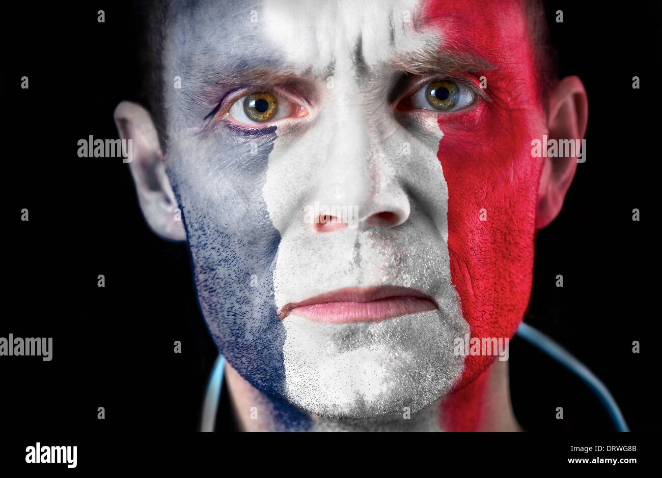 Un regard intense d'un supporter de football avec leur visage peint avec le drapeau français. Banque D'Images