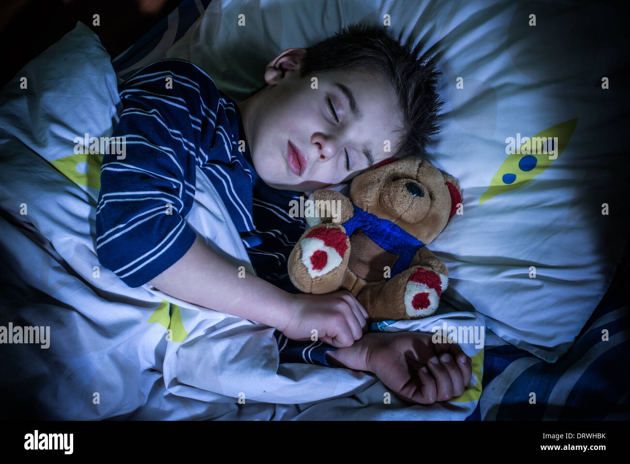 Enfant endormi avec son ours en peluche. Banque D'Images