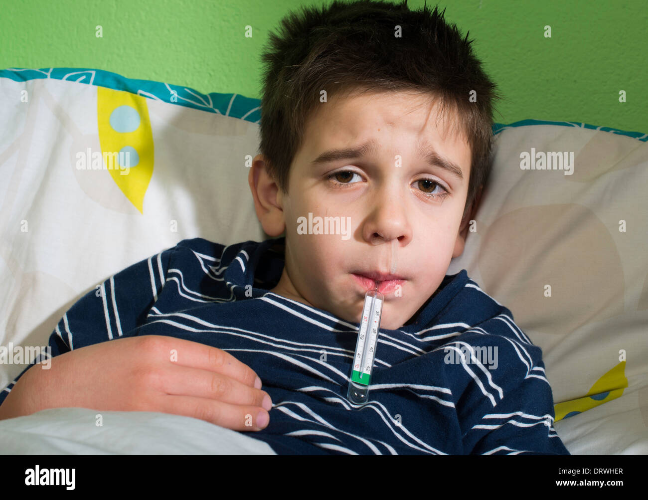 Enfant malade au lit. La mesure de la température avec un thermomètre. Banque D'Images