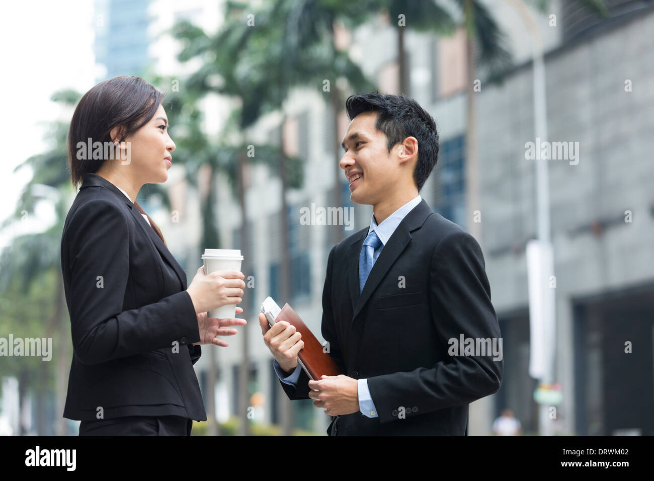Des collègues chinois heureux de marcher à l'extérieur du bureau et de parler les uns aux autres. Banque D'Images