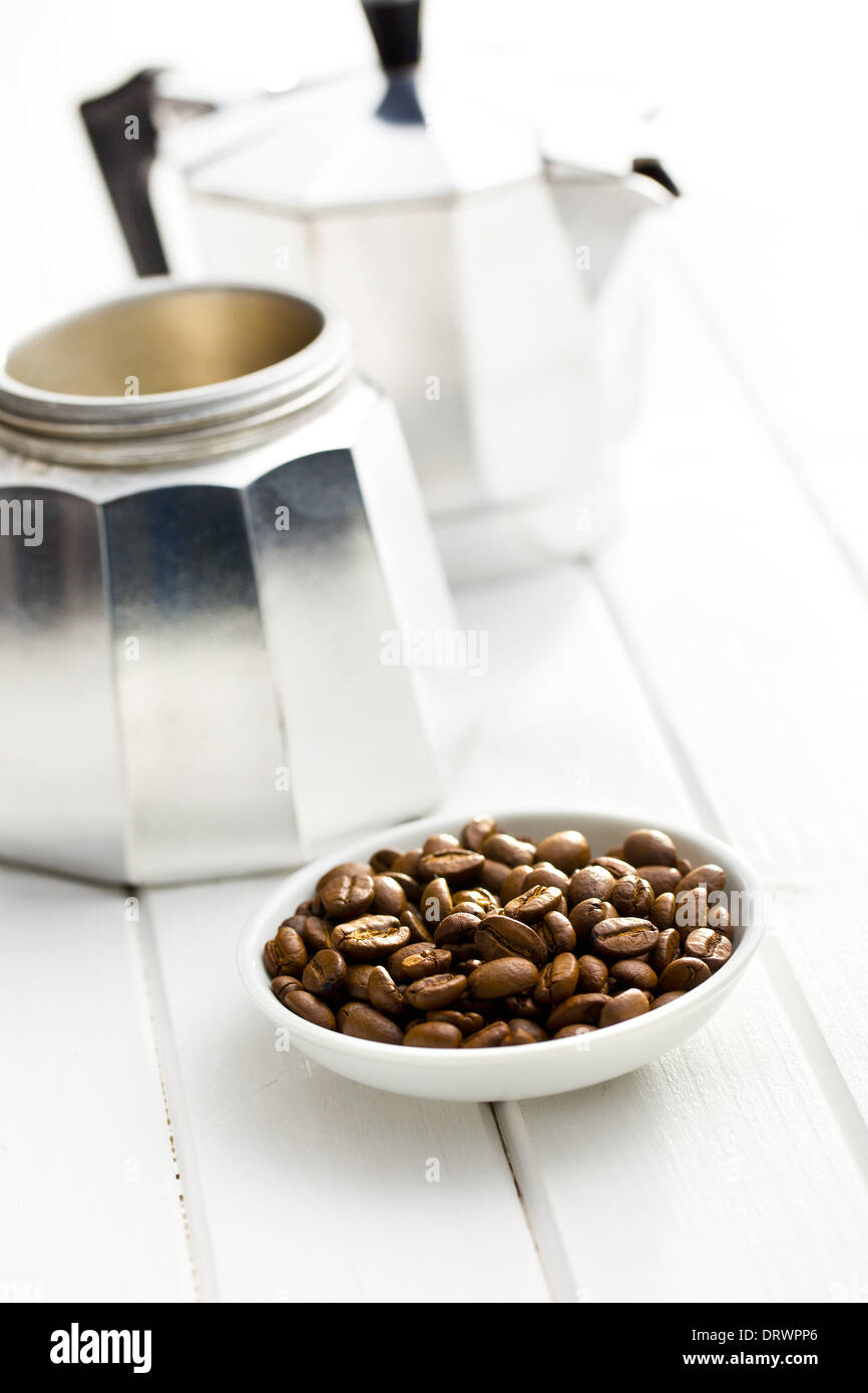 Les grains de café dans un bol de cafetière sur fond de bois blanc Banque D'Images