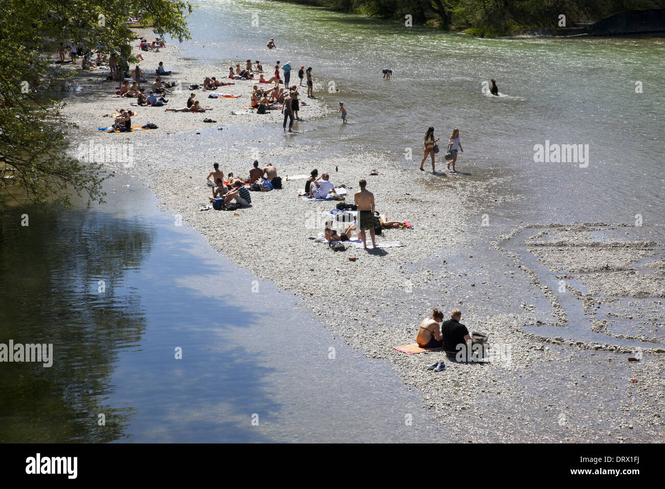Les gens se rassemblent sur les rives de l'Isar stony river à Munich pour se rafraîchir et profiter du soleil de l'été. Banque D'Images