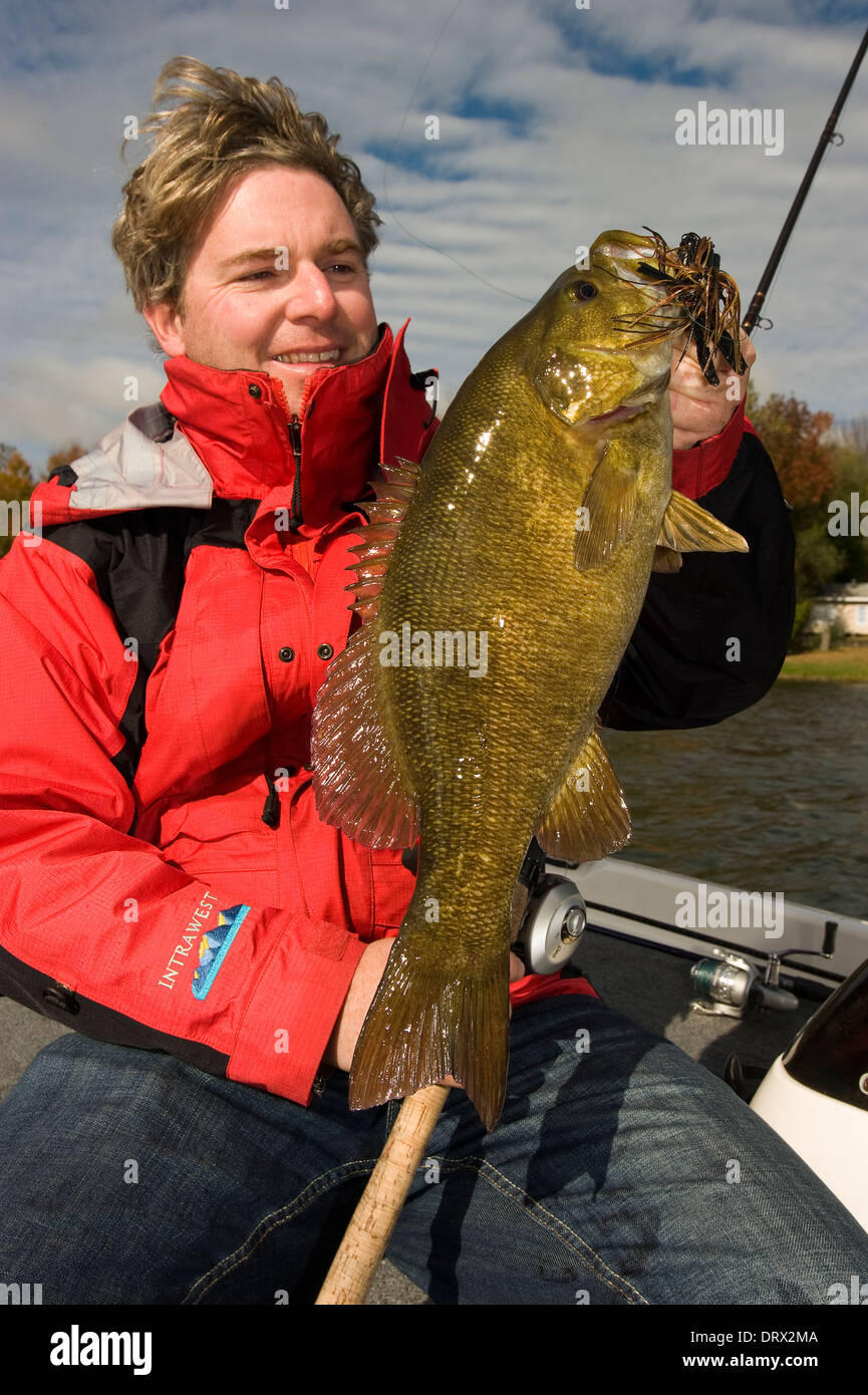 Maintenant le pêcheur à l'achigan à petite bouche ils pris dans un bateau sur un lac dans le Nord de l'Ontario. Banque D'Images