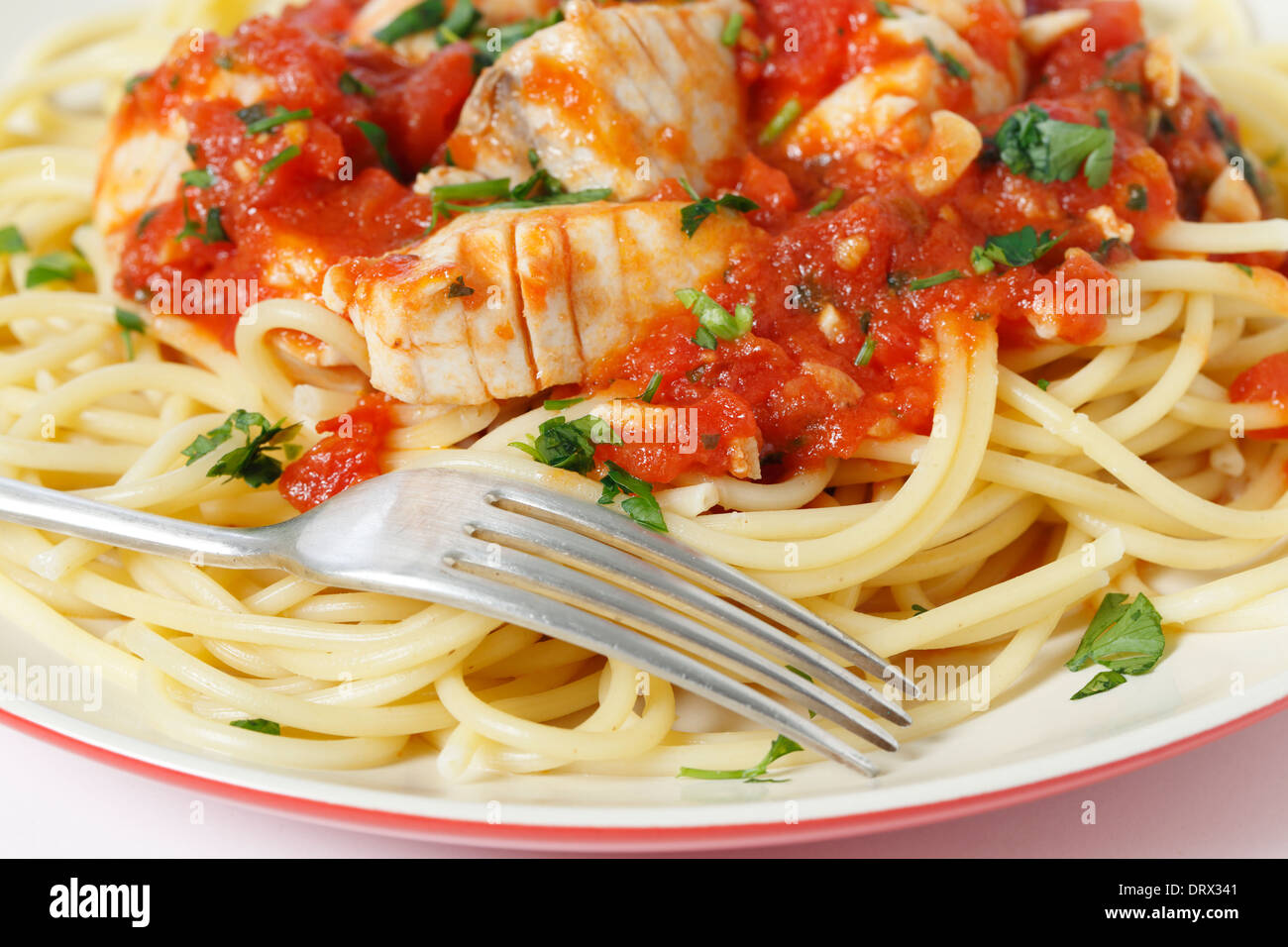 Le poisson frais dans la sauce arrabbiata, servi sur les spaghettis et à la fourchette, avec un sprinked garnir persil, gros plan Banque D'Images