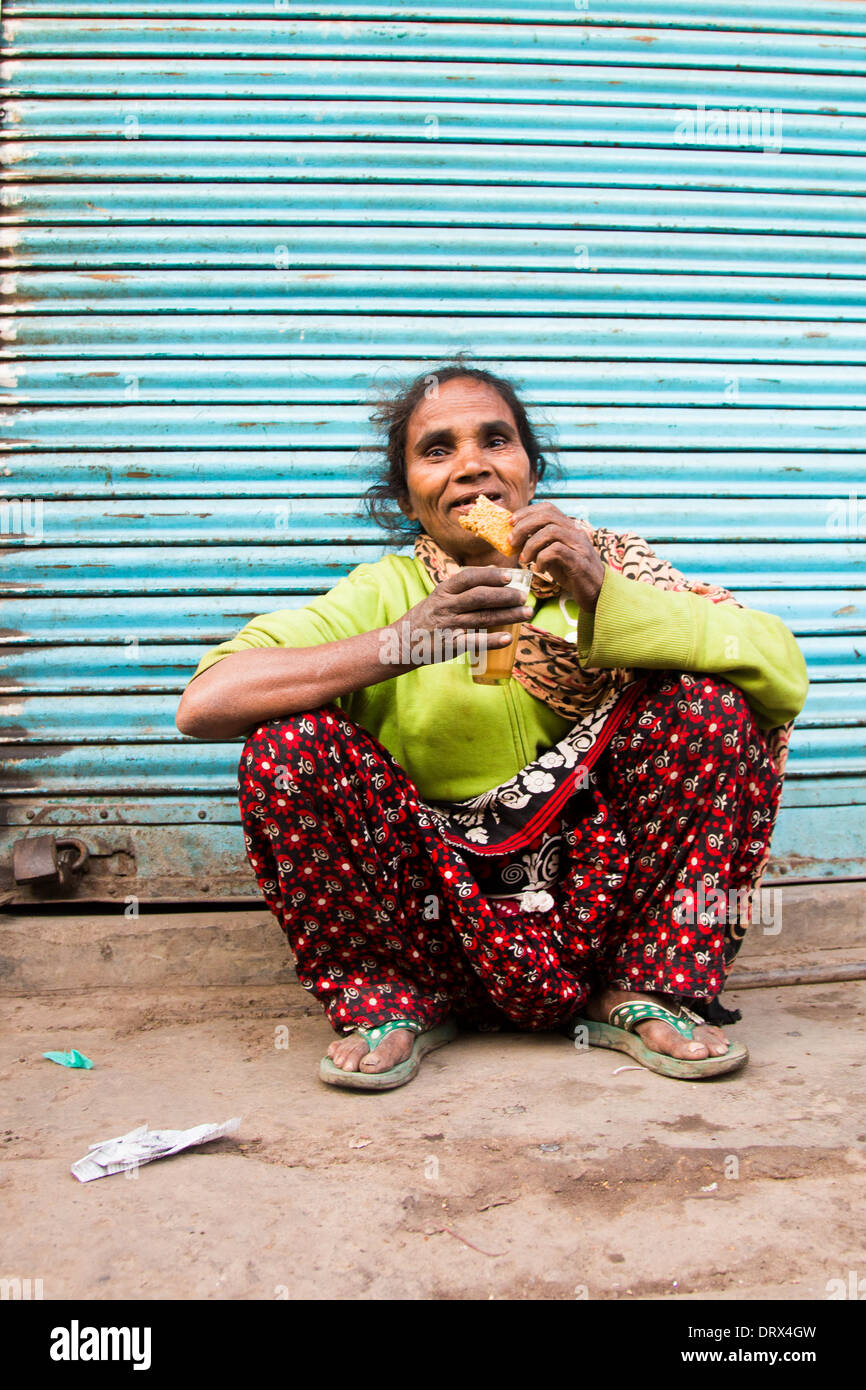 Femme à boire le thé et manger un biscuit Old Delhi, Inde Banque D'Images