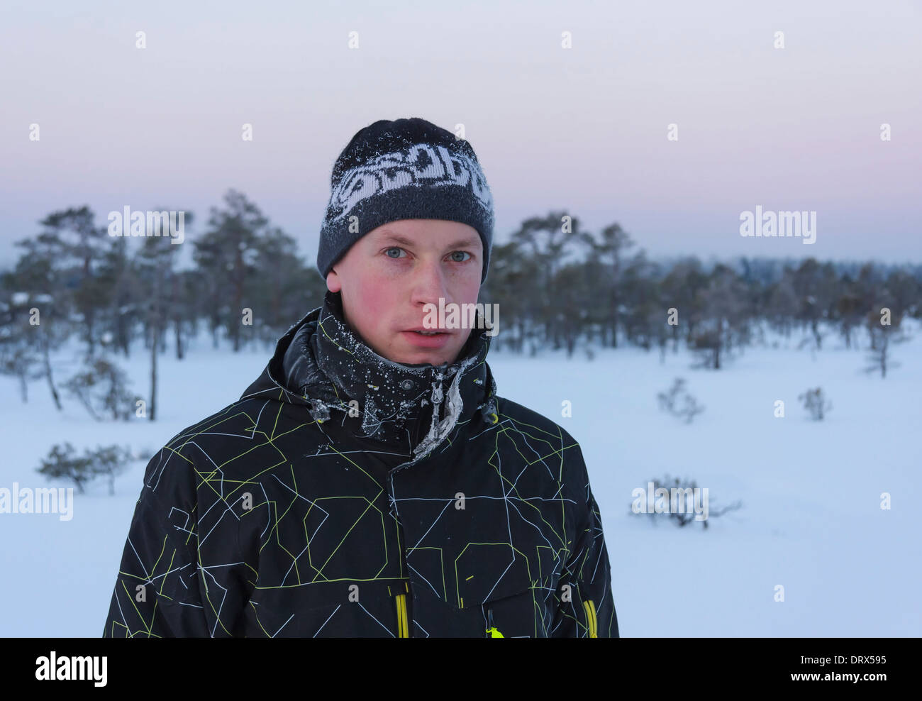 Portrait d'un jeune homme avec des vêtements et un chapeau givré dans un marais tôt dans la matinée d'hiver Banque D'Images