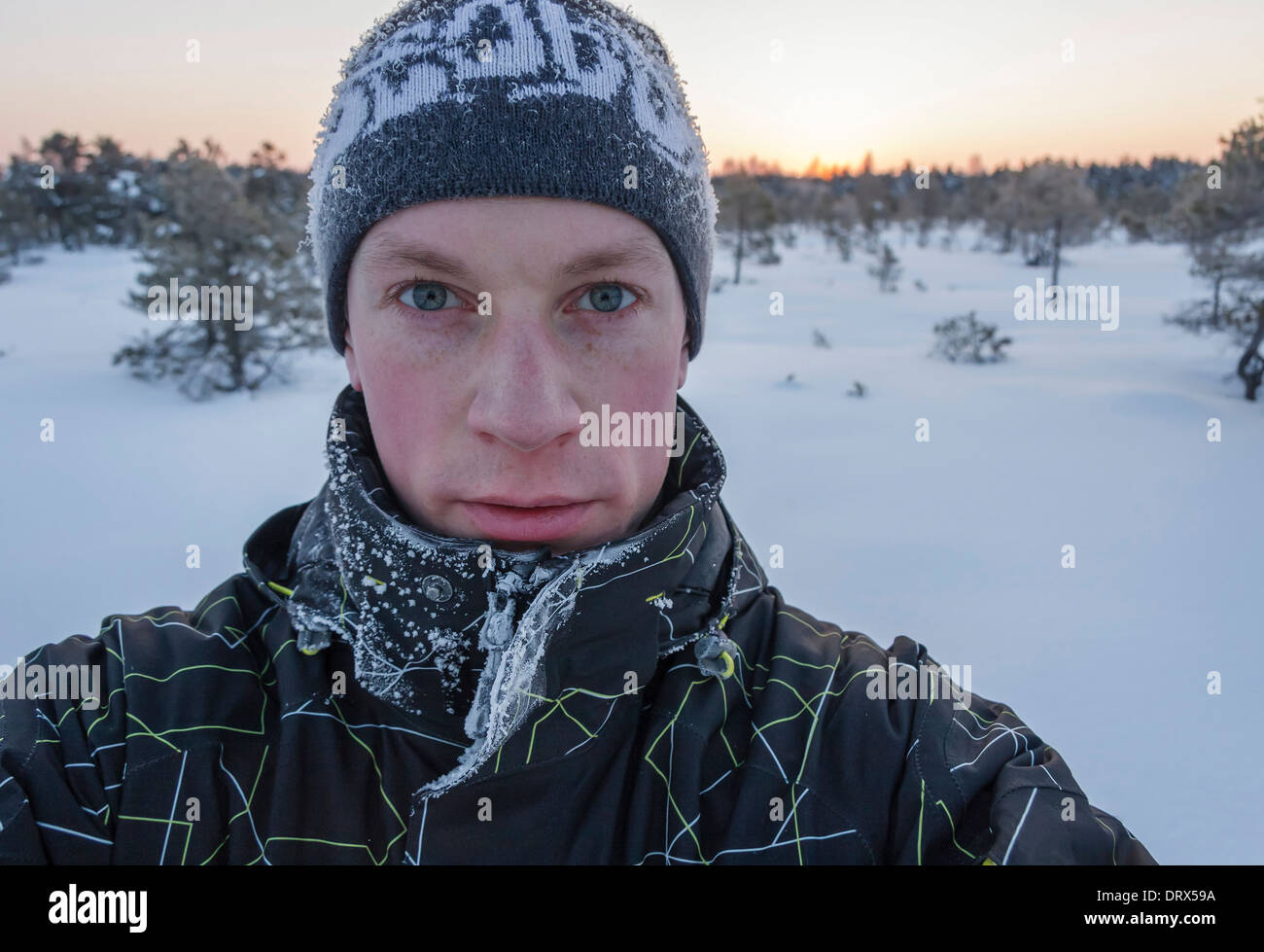 Portrait d'un jeune homme avec des vêtements et un chapeau givré dans un marais tôt dans la matinée d'hiver Banque D'Images