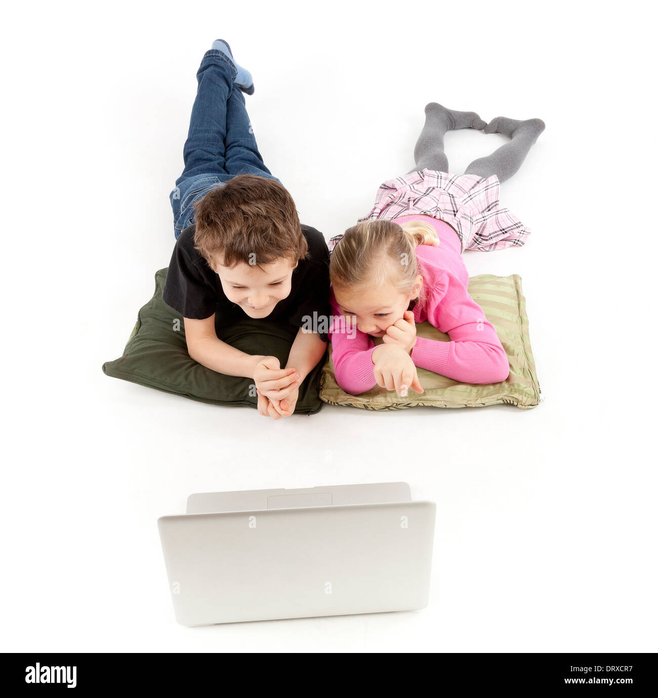 Les enfants sont couchés et regardant l'ordinateur portable d'argent Banque D'Images