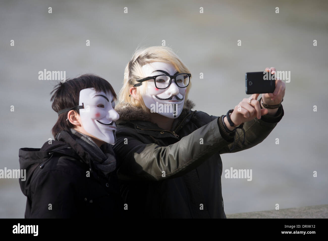 Un couple portant des masques anonymes posent pour leur propre photo selfies. Banque D'Images