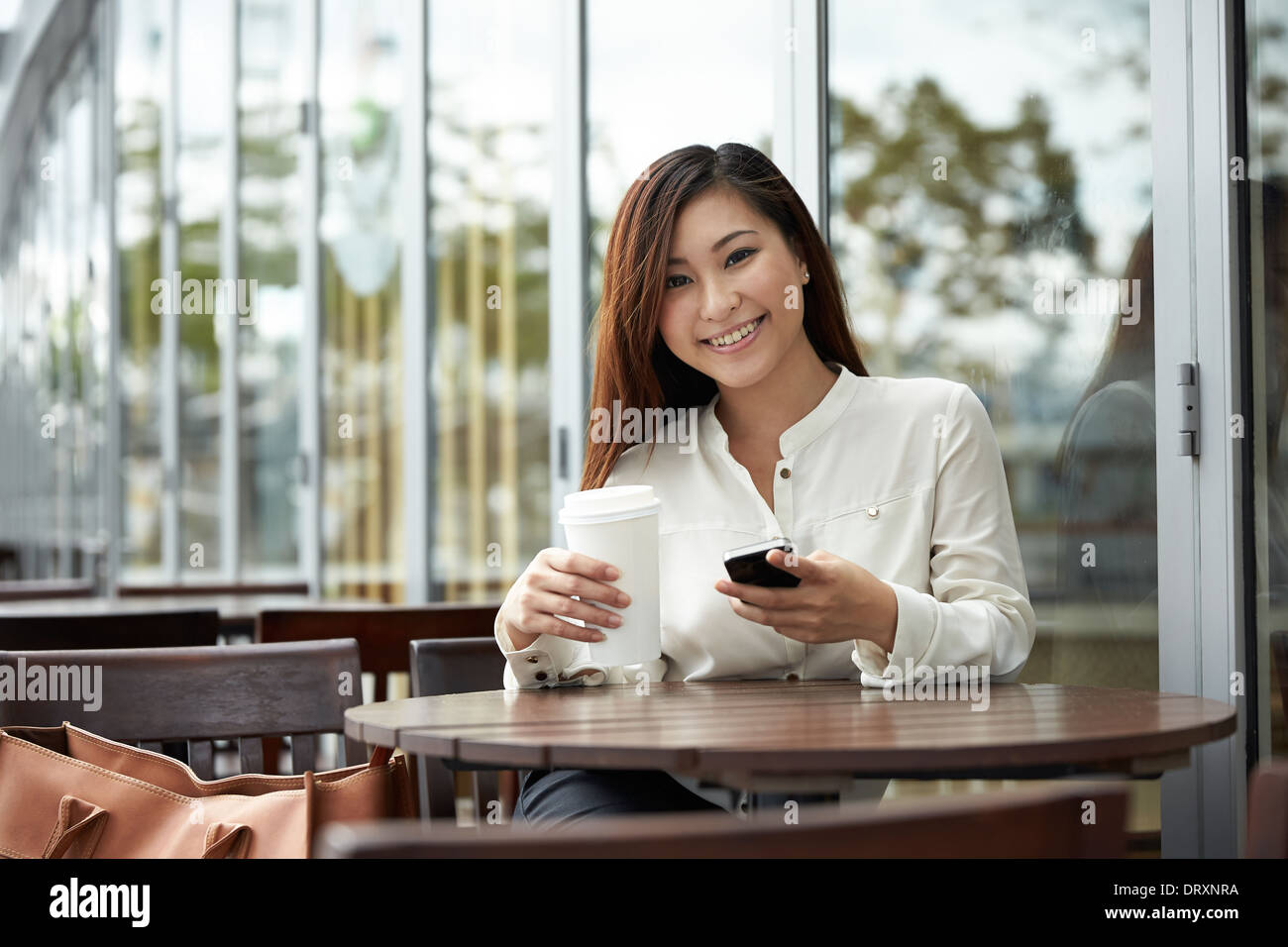 Portrait d'une femme chinoise en utilisant un téléphone intelligent dans un café Banque D'Images