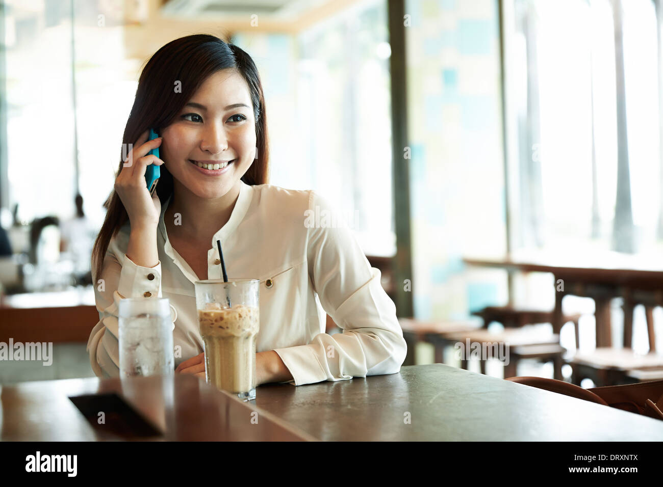 Portrait d'une femme chinoise en utilisant un téléphone intelligent dans un café Banque D'Images