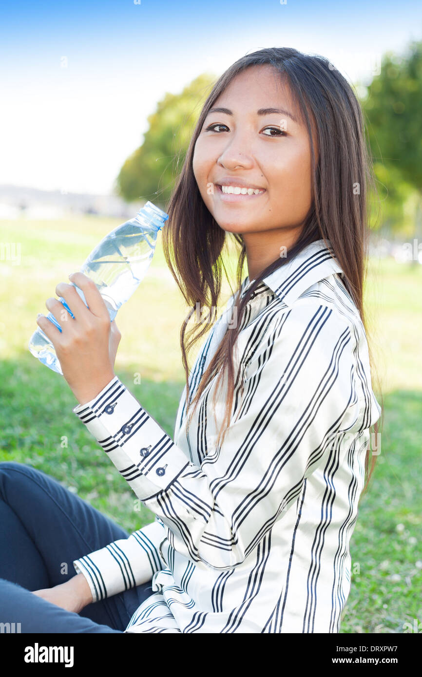 Portrait d'une jeune fille asiatique dans un parc avec une bouteille d'eau Banque D'Images