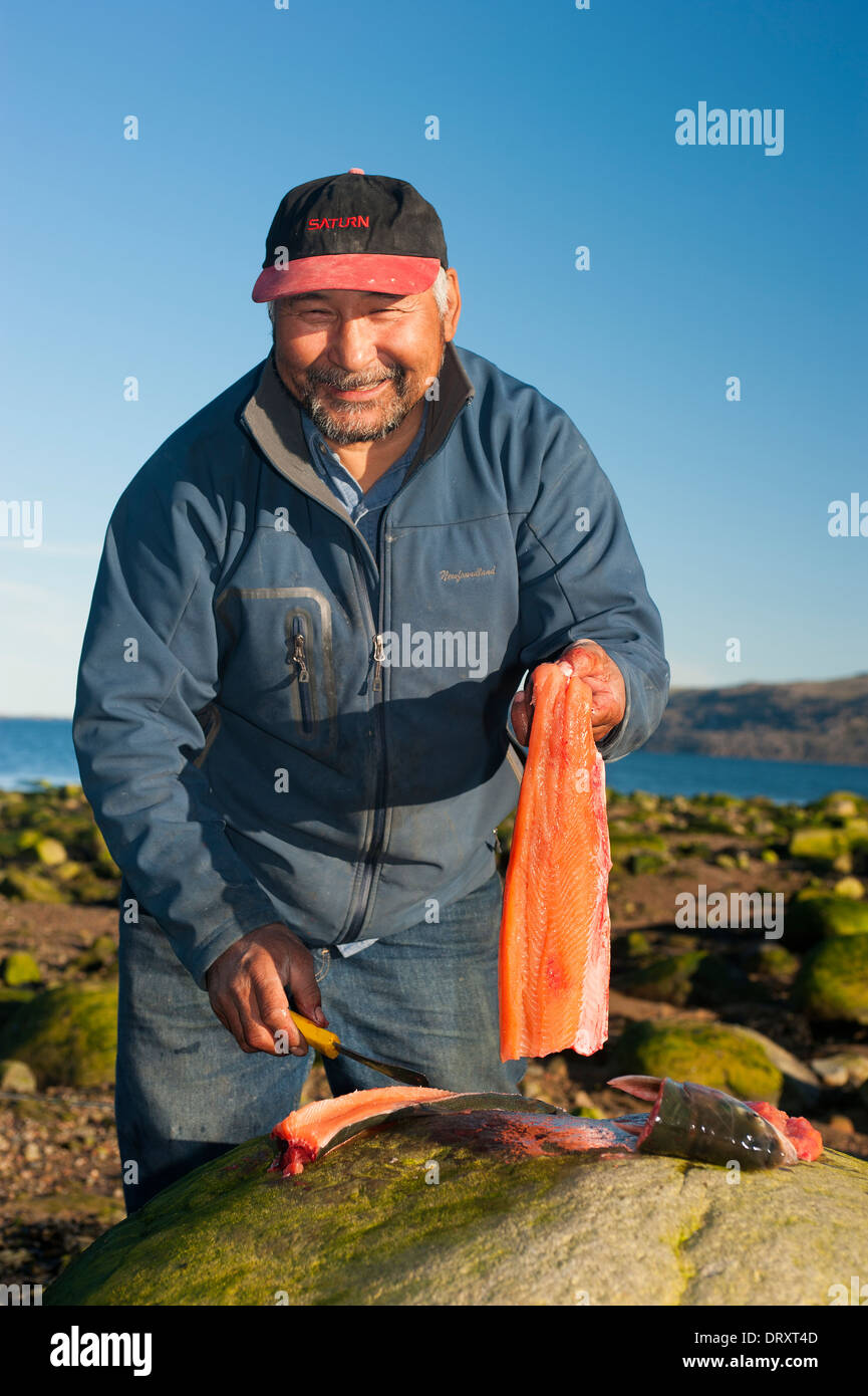 Un guide de pêche Inuit les filets de poisson pris à la mouche dans les eaux de l'Arctique. Banque D'Images