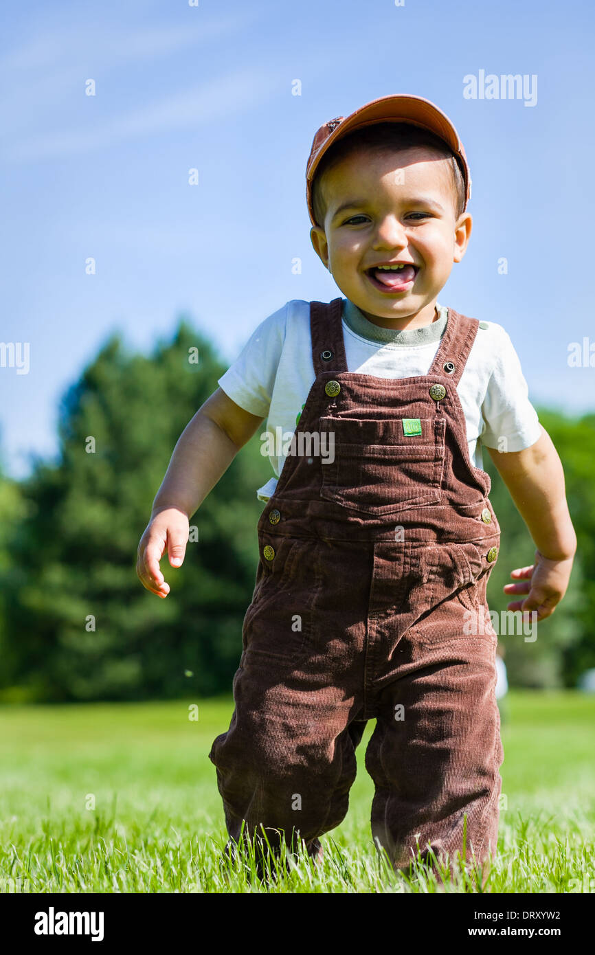 Jeune bébé garçon en salopette et cap en marche dans l'herbe Photo Stock -  Alamy